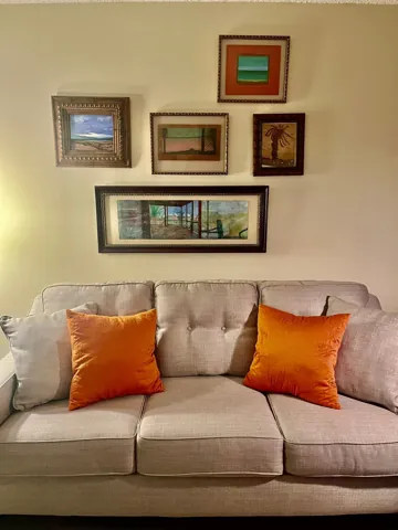 Orange cushions and framed artwork above a sofa