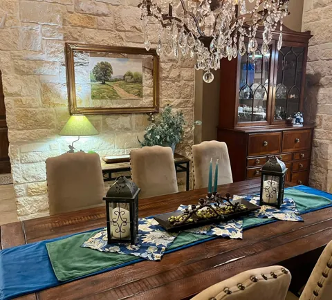 A dining table with a chandelier and collected decorative accents