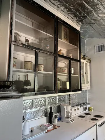 Glass-front kitchen cupboards filled with dishes and collected objects