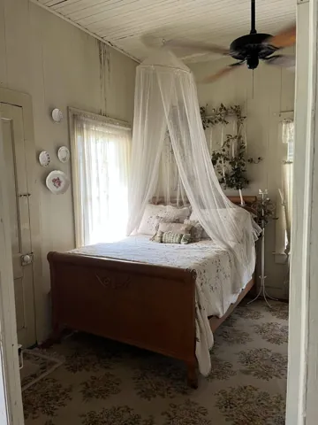 A softly draped wooden bed beside a bright window