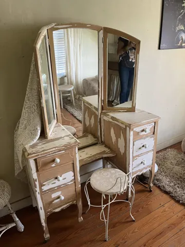 A vintage dressing table with an oval mirror and small stool