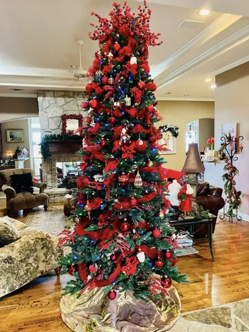 A tall Christmas tree with red flowers in a bright living space