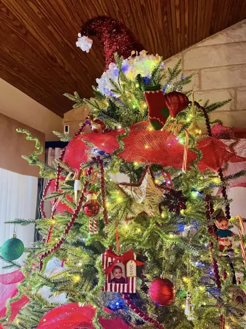 A Christmas tree topped with colorful ribbon and floral stems