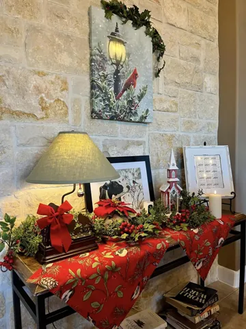 A narrow table with red holiday flowers against a stone wall