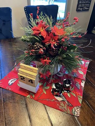 A red and green floral centerpiece on a dining table