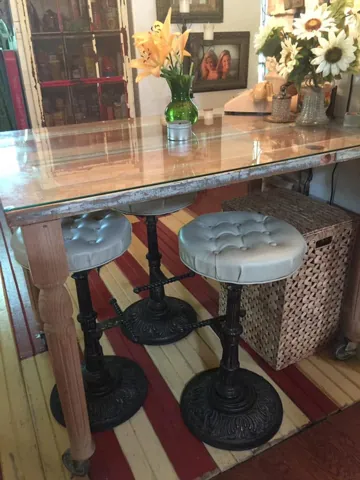 A narrow wood table with two patterned stools beneath a large mirror
