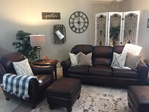A brown sectional sofa with patterned cushions and a round wall clock
